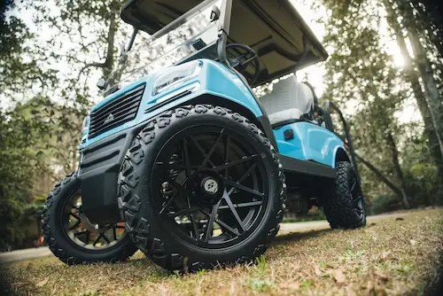 Blue golf cart on grass with large black wheels