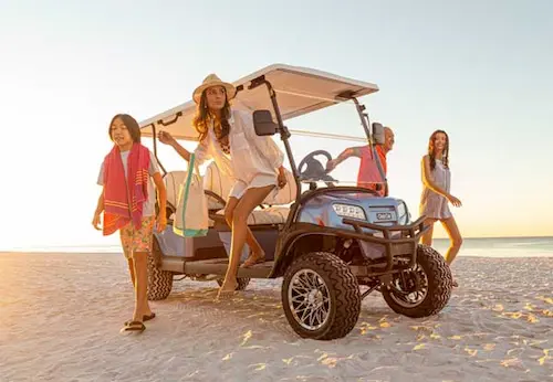 Group of friends enjoying a beach outing with a golf cart