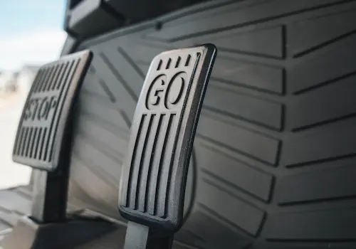 Close-up of vehicle pedals labeled Go and Stop